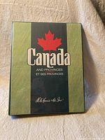 Front cover of the vintage Canada stamp album with a red maple leaf and title in English and French.