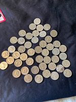 A triangular arrangement of 46 Canadian nickels in varying conditions spread out on a dark fabric background.