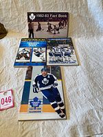Five vintage Toronto Maple Leaf Year Books and Fact Book laid out on a light surface with a small evidence card visible.
