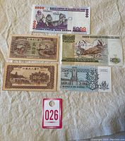 Overhead shot of all five banknotes on white fabric background