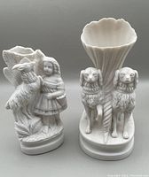 Photo of two white Parian ware vases, one shell-shaped with two dogs, one with girl and goat figurine
