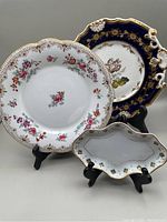 Three antique porcelain items displayed including Adderleys floral plate, Limoges coin dish, and floral decorative plate