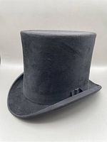 Front and side angled view of the black antique top hat showing shape, texture, and grosgrain ribbon detail.