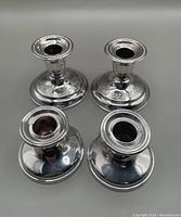 Four small Regency Plate candlesticks by Birks, grouped with damage visible on one piece.