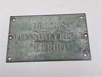 Front of rectangular embossed metal advertising plaque with text: 'BROOKS RAINS ONLY RIVAL DETROIT'. Six mounting holes visible.