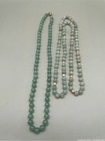Two green stone bead necklaces laid side by side showing difference in bead color and style