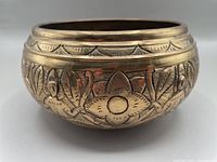 Front close-up view showing etched floral and leaf patterns on the brass singing bowl exterior.