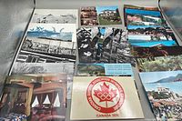 Wide view of assorted vintage postcards showing both black and white and color images including Canadian and international scenes, Olympic Association logo postcard visible