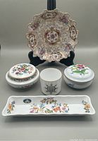 Porcelain lot items arranged on grey background showing Pompadour shallow bowl, two covered trinket boxes, small cup, and pen tray.