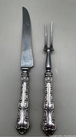 Full view of the carving knife and carving fork side by side on a neutral background