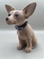 Front left angle view of the Taco Bell Chihuahua bobble head showing details of felt covering, ears, eyes, nose and collar with tag