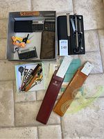 Overhead view of calculators, slide rules, 3-hole punch and drafting tools in storage box