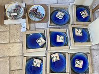 Top-down view of eight cobalt blue Asian plates in individual cardboard boxes with collection labels.