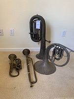All four instruments arranged on carpet: French horn, tuba, trumpet and bugle