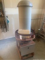 Full view of tall secondary coil with paper tube, metal toroid top and wooden rolling base