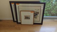 Three framed duck art pieces leaning against the wall, showing overall view including two larger frames and a smaller one with neutral mats.