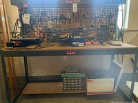 Front view of Gorilla Rack workbench with pegboard, shelves and parts organizer on surface and bottom shelf