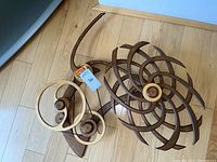 Overhead view of assembled kinetic wood sculpture on hardwood floor showing spiral gear components