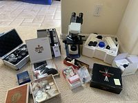 Lot contents overview showing microscope, accessories in cases and boxes, and various optical components.