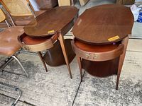 Pair of oval wooden end tables with drawers open showing lined drawer and lower shelf, wood has some superficial scratches and small nicks
