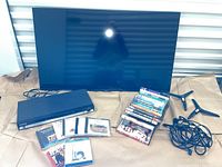 Photo showing Samsung 43 inch TV screen, Samsung DVD player, two detachable TV legs, cables, and assorted DVDs and CDs spread on paper.