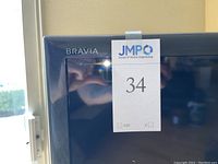 Close-up of the upper left corner of the TV screen showing 'BRAVIA' logo and lot number sticker '34'.