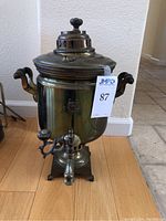 Front view of the vintage metal samovar with wooden side handles and spigot, showing overall condition and design.