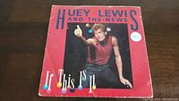 Front of the red record sleeve featuring Huey Lewis giving a thumbs-up and title text.