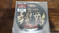 Full view of the Motley Crue picture disc inside sealed plastic sleeve, showing band members in costume and track names.