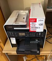 Front view of Canon ImageCLASS MF4880DW printer with Canon 128 ink cartridge box on top.
