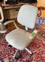Side-angle view of the Steelcase office chair showing seat, backrest, armrest, and casters on a red patterned rug.