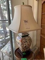 Overall view of lamp with floral ceramic body, wood base, fabric shade
