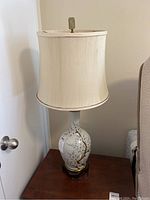 Full view of the lamp showing ceramic floral base on wooden stand with fabric shade on top