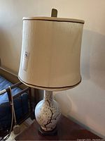 Full view of the lamp showing ceramic base with floral design and fabric shade with damage