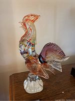Side view of Murano glass rooster showing detailed internal multicolored ribbons and pinkish-red upper portions