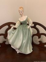Front view of Royal Doulton Fair Lady figurine in green dress with cream sleeves showing facial details and flowing dress.