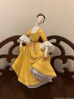 Front three-quarter view of Royal Doulton Stephanie HN2807 figurine in yellow dress showing detailed paint and facial features.