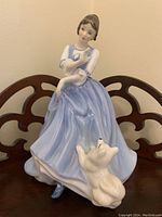 Front view of Royal Doulton Lorraine figurine showing woman in blue dress and white dog at her feet.