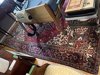 General top-down view of red oriental rug under hospital bed and chairs.