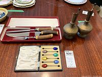 Full view of the lot items including the 6 sterling silver enamelled spoons in case, 2 brass jugs, and carving set in case