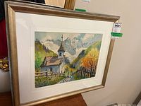 Framed watercolour painting signed Moder, showing a mountainous rural scene, chapel, and figures on path.