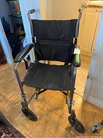 Front view of the folding wheelchair showing canvas seat and armrests