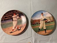 Front view of two 8-inch round collector plates featuring Cy Young batting and Jimmy Fox pitching during baseball games.