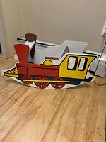 Side view of the vintage wooden train rocking car showing detailed colorful paint resembling a steam locomotive.