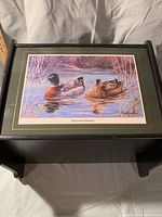 Front view close-up of the dark green wooden magazine holder featuring the 'Backwater Mallard' duck print with pond background.