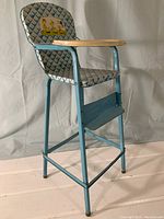 Full view of the blue plaid doll high chair with wooden tray and metal footrest.