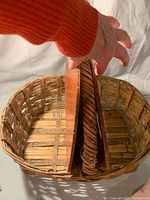 Top-down view showing wooden lid partially open revealing inside of large woven wicker basket with wooden slat lid.