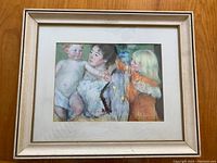 Framed print showing full artwork of mother with two children, soft colors and pastel style, in cream wooden frame with double matting.
