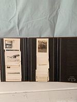 Open tri-fold Fotofile album showing stacks of vintage black-and-white photos mounted on black pages