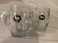 Pair of two clear glass Youngs Draught beer mugs with the white sheep logo and etched branding.